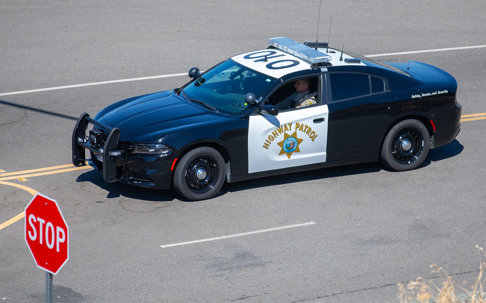 A California Highway Patrol Dodge Charger approaches a stop sign at an intersection