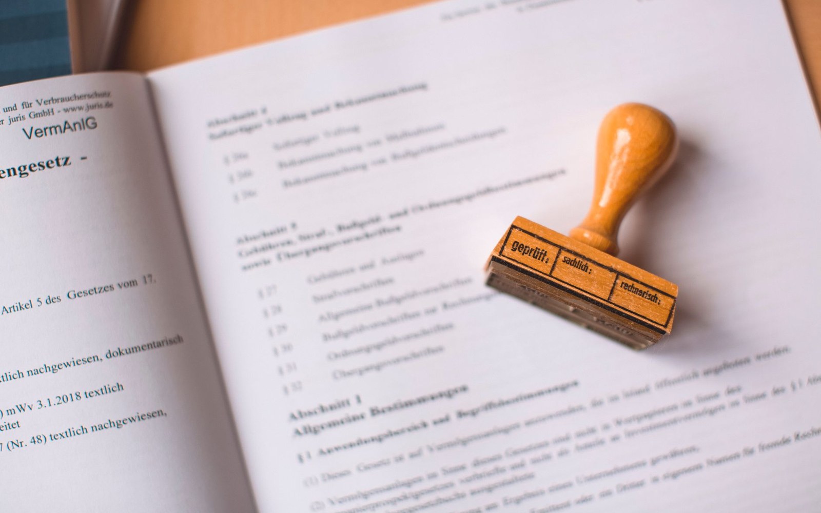 A wooden approval stamp resting on an open German legal document