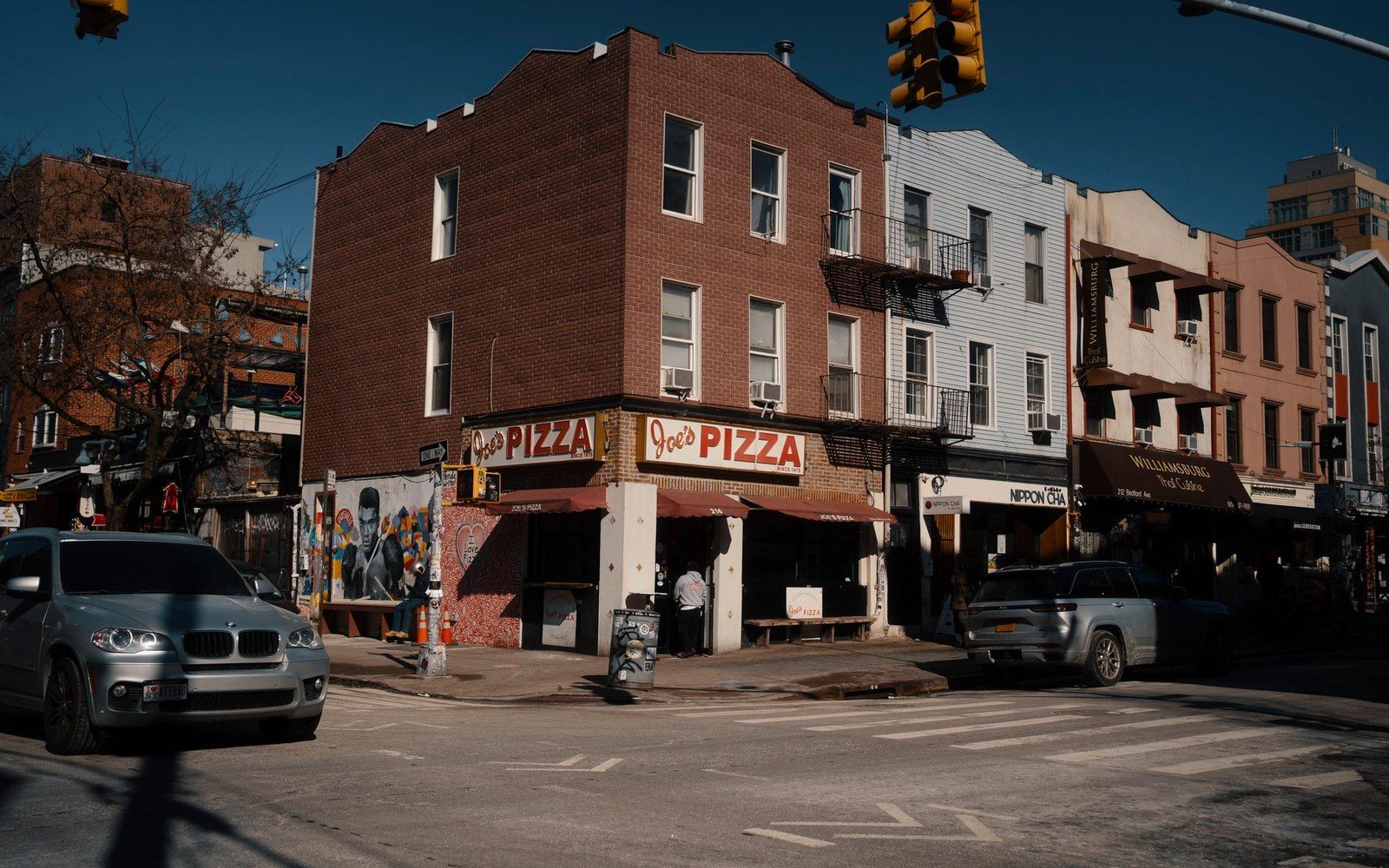 Joe's Pizza storefront on a brick corner building at a busy street crossing