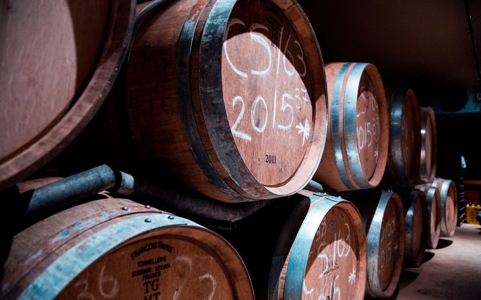 Stacked oak wine barrels marked with vintage years and lot numbers in a cellar