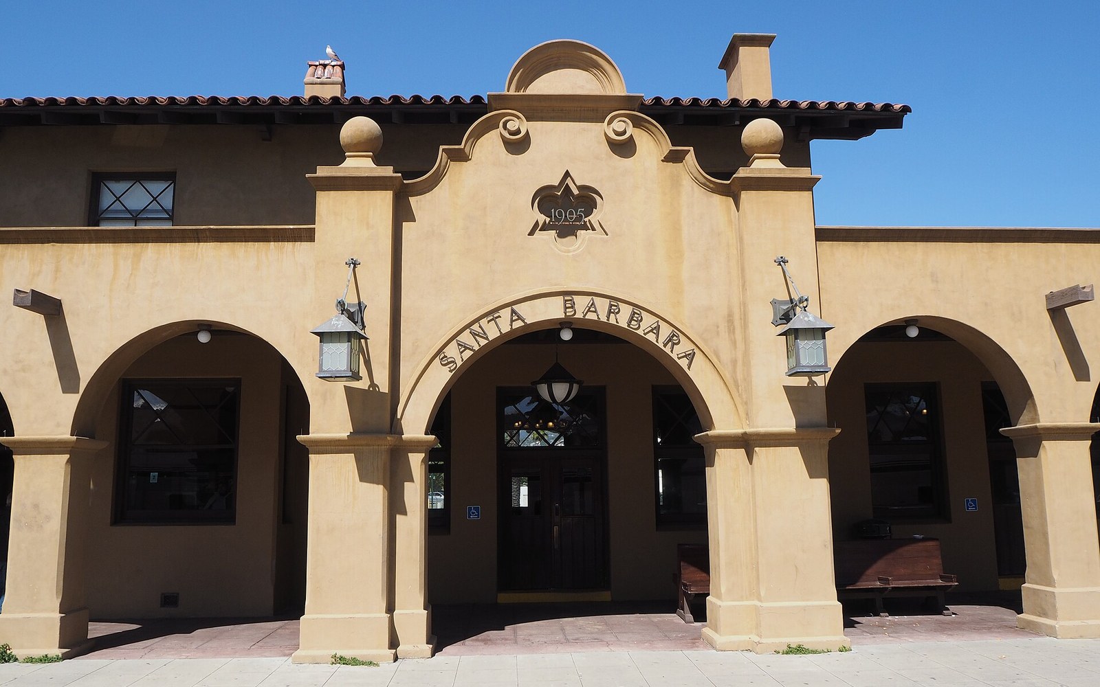 Arched facade of the Santa Barbara Amtrak station with terracotta roof tiles and hanging lanterns