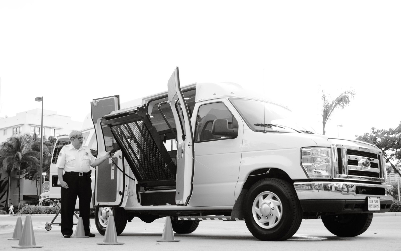 A uniformed driver operates a wheelchair lift on the side door of a van